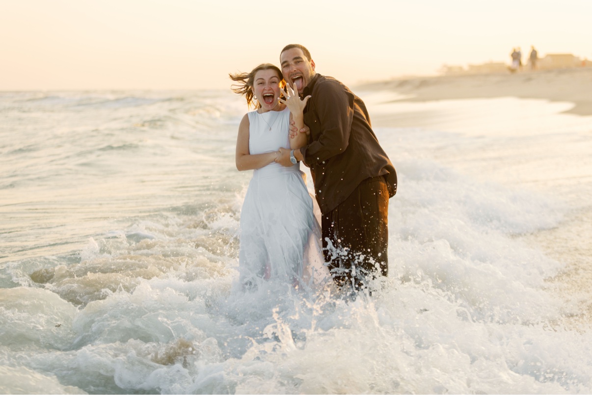 Couple celebrating in the surf at golden hour after a surprise proposal at a Long Island beach