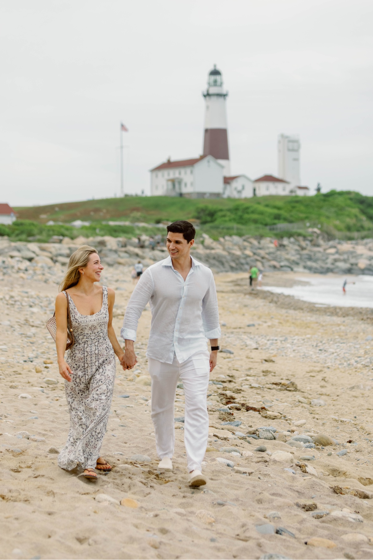 A couple walking hand in hand along the beach below Montauk Lighthouse, Long Island, just after the proposal