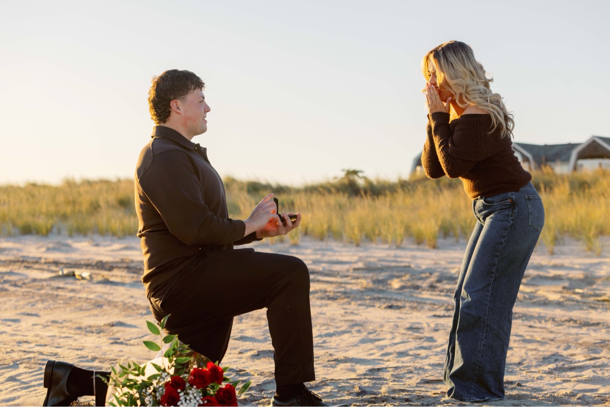 Surprise proposal at Cooper's Beach, Southampton, Long Island — on one knee with the ring box open, her hands over her face in surprise