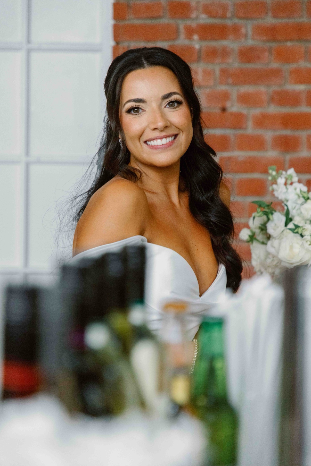 Smiling bride at the Bourne Mansion bar with a brick wall behind her