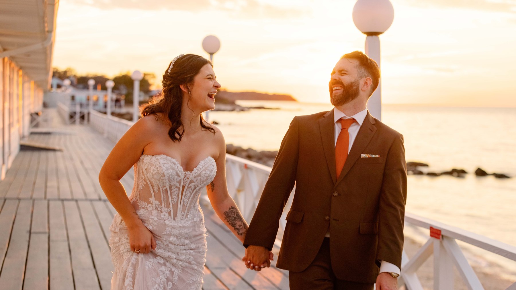 Bride and groom laughing together on a waterfront deck at sunset on Long Island — Long Island wedding photographer