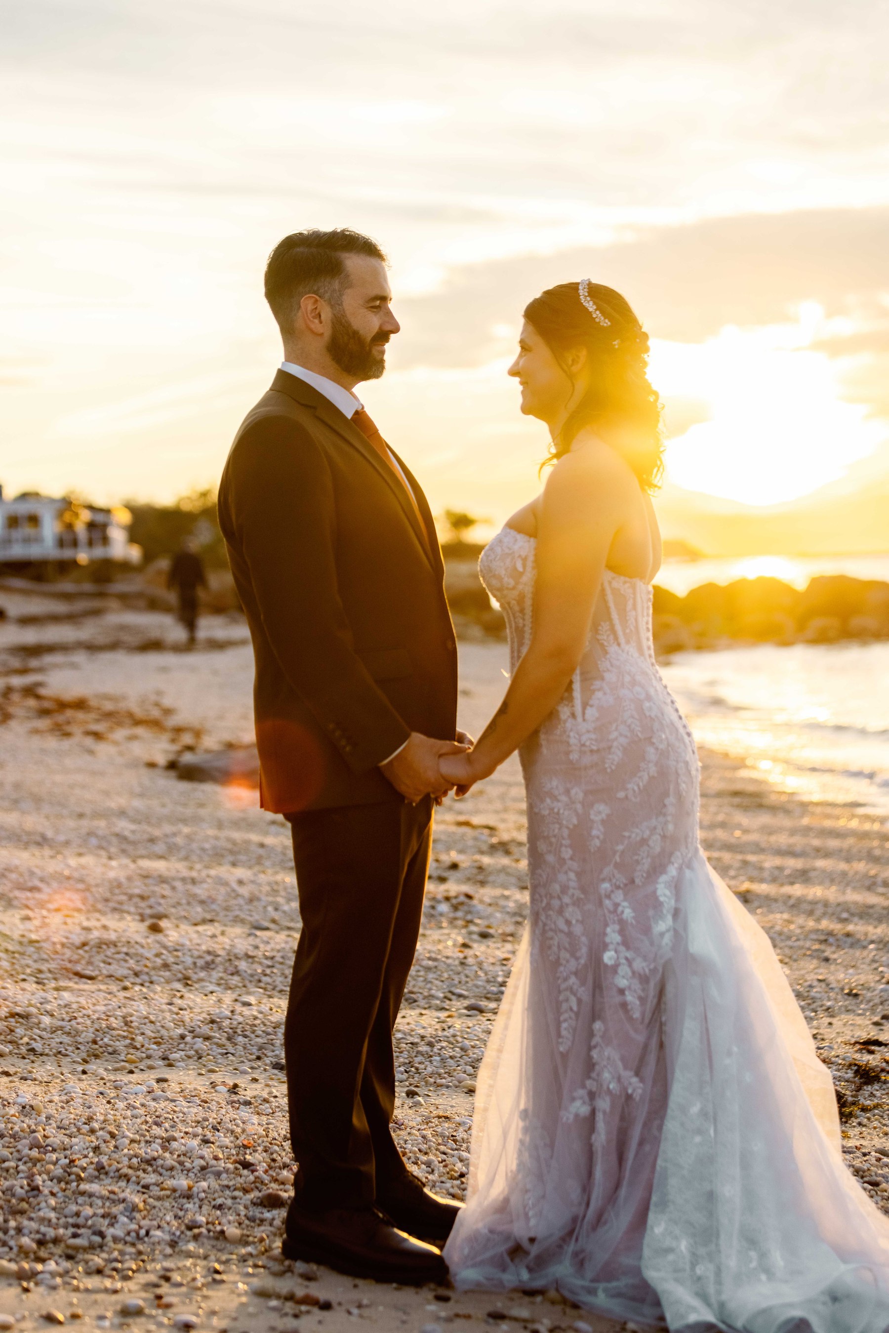 Newlyweds facing each other on the beach at sunset