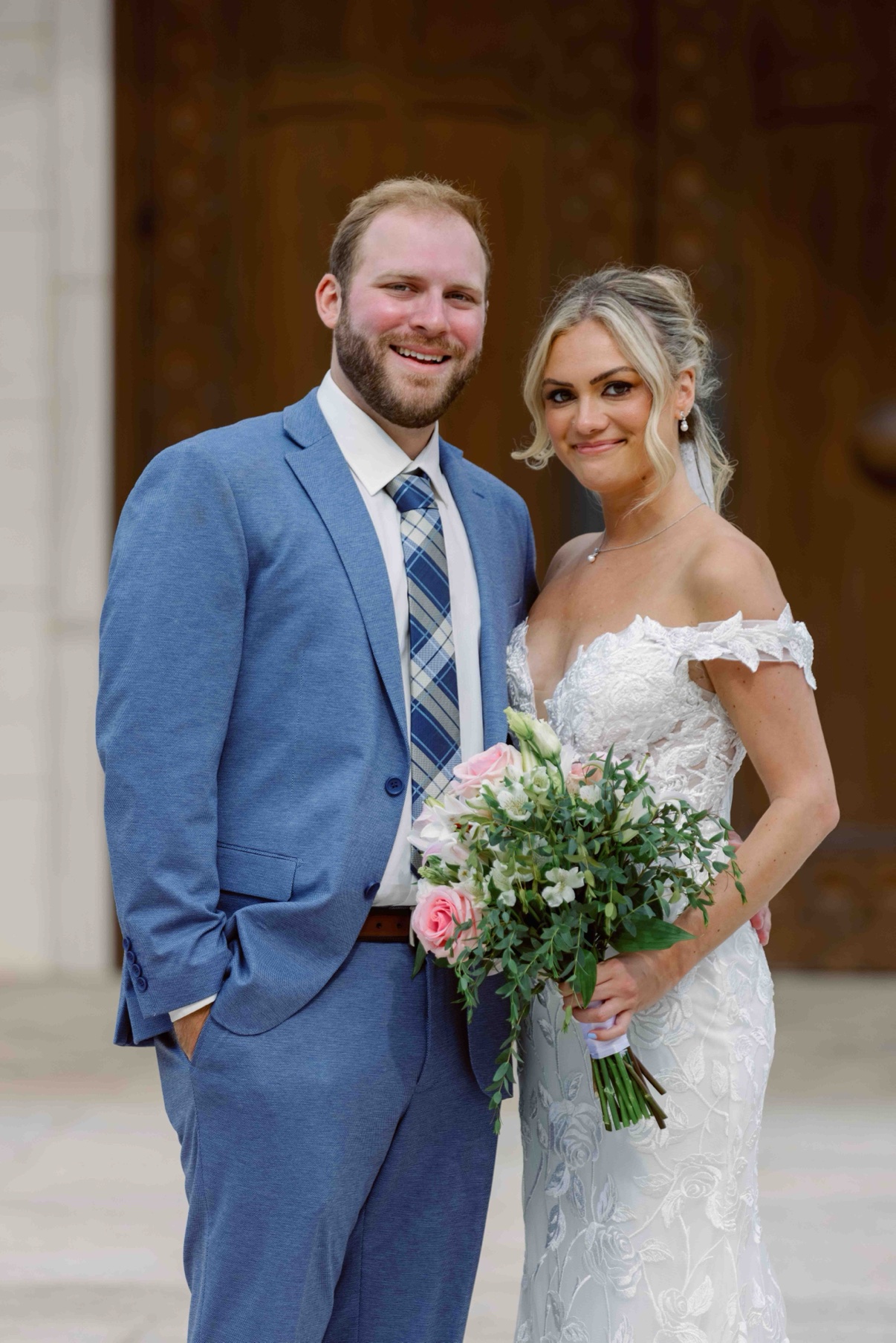 Bride and groom smiling together outside the wooden church doors at The Muses in Southampton