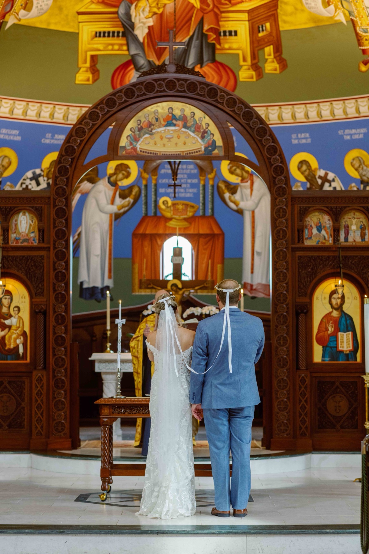 The couple wearing ceremonial crowns during their wedding ceremony inside the mosaic church at The Muses
