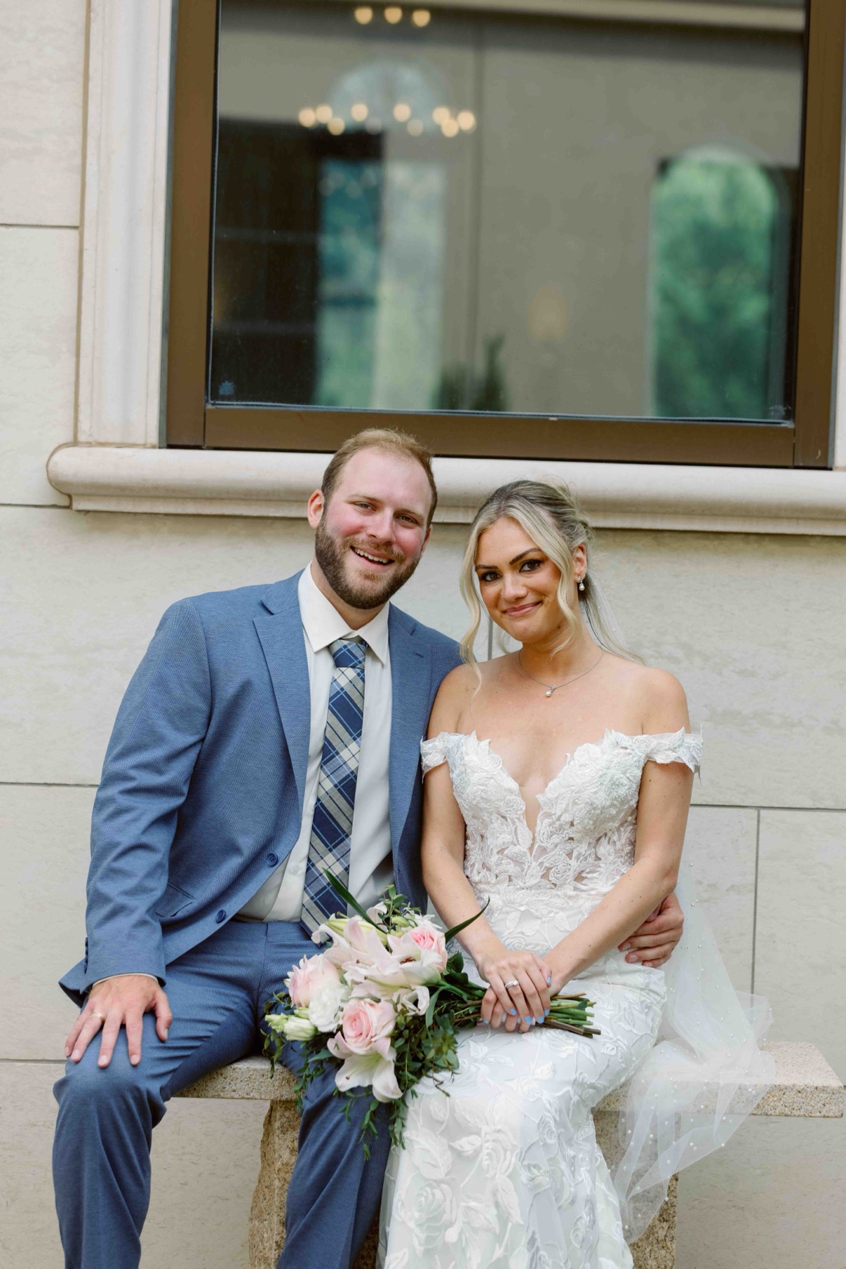 Bride and groom seated together on a stone bench by the window at The Muses in Southampton