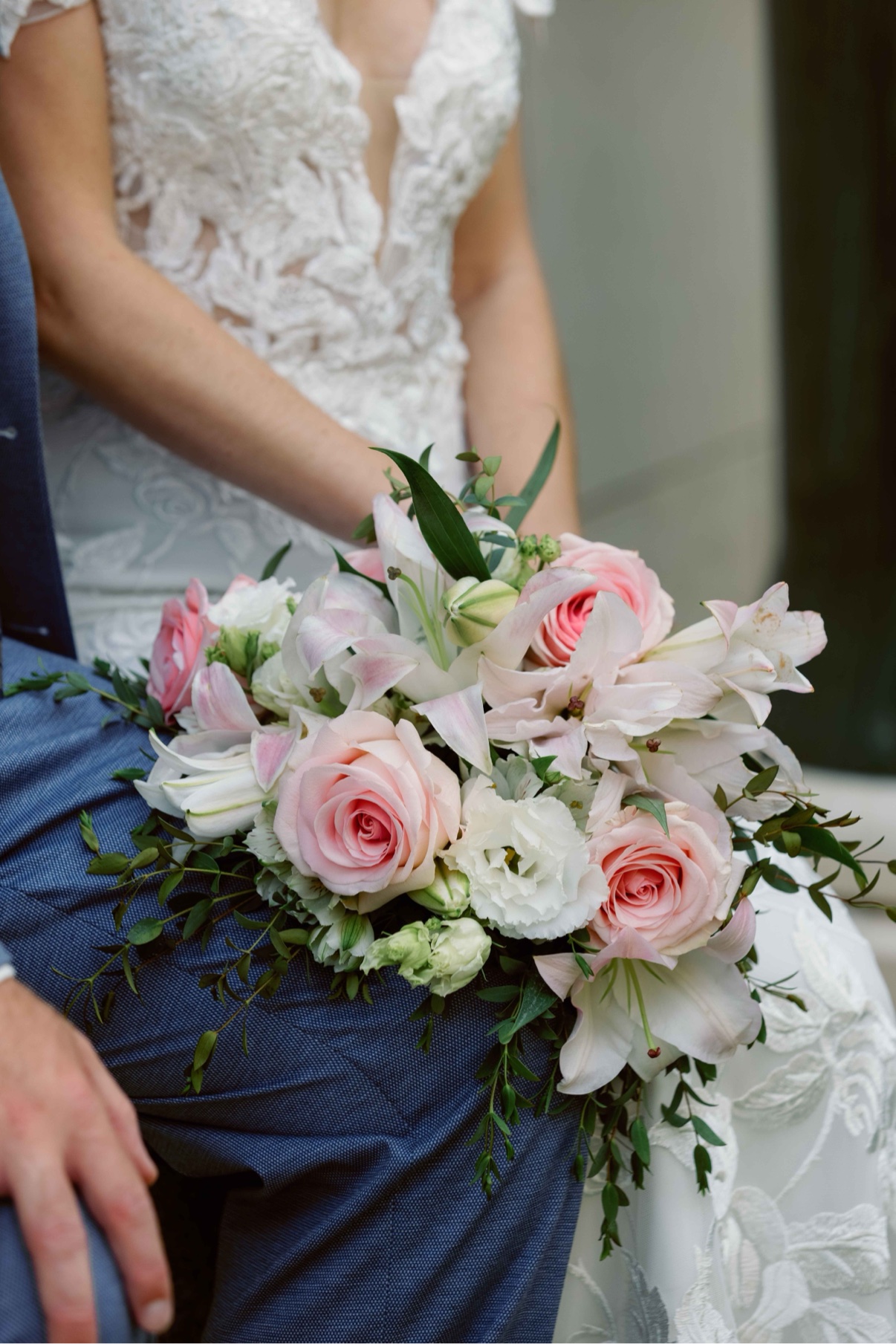 Pink roses and lilies resting on the groom’s lap