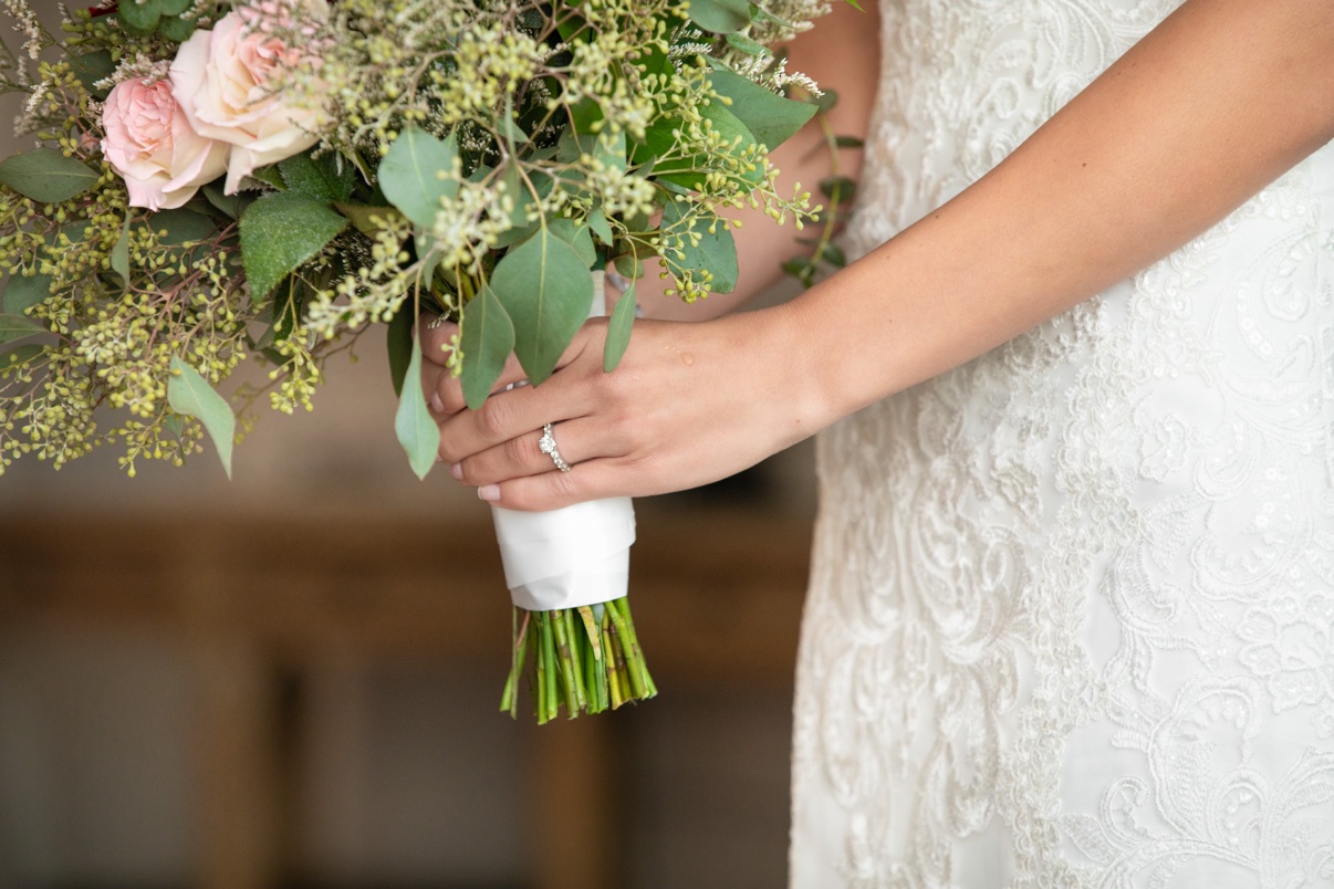 Bride’s hands holding her bouquet with her wedding ring visible