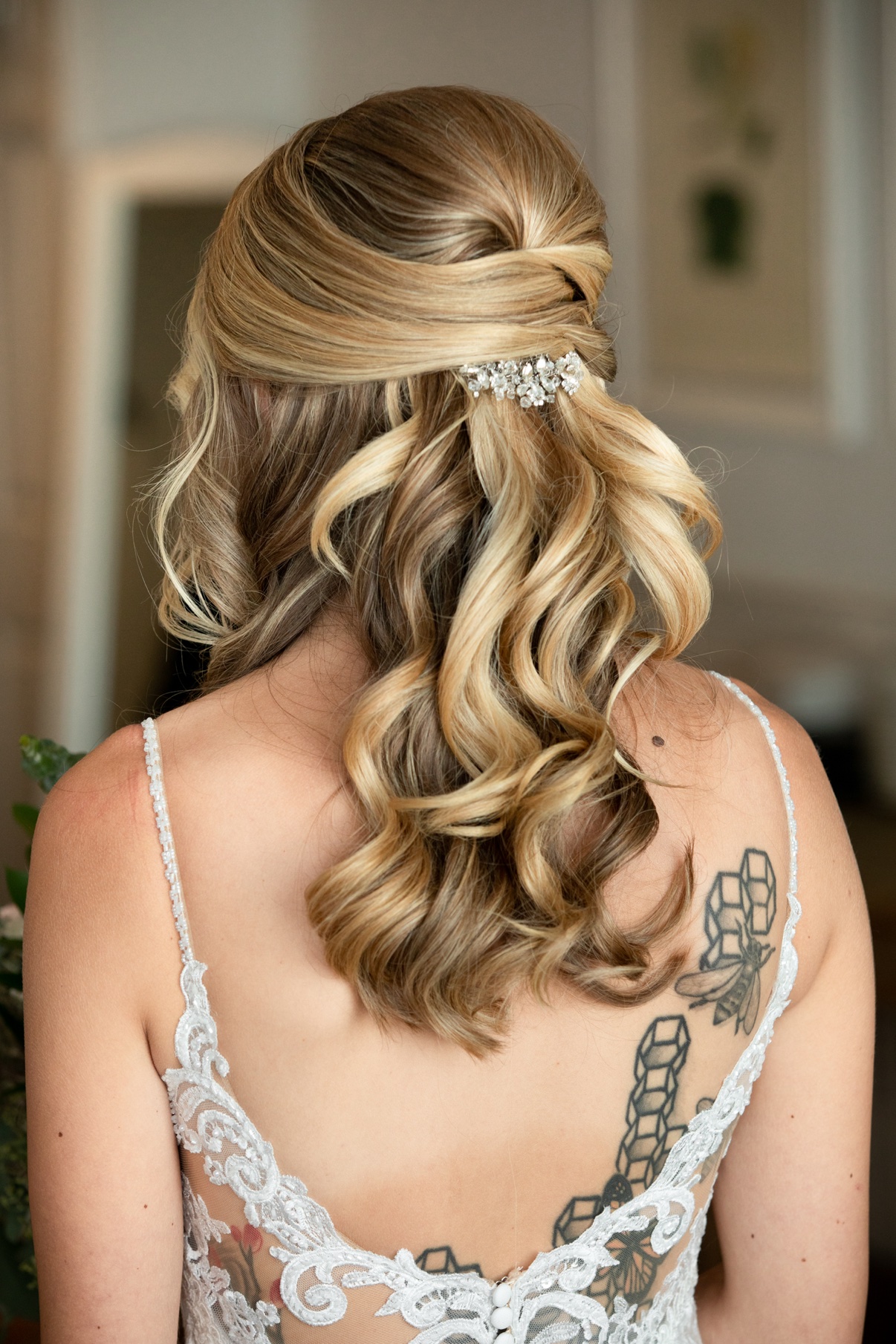 Back of the bride’s styled curls with a crystal hairpiece and lace dress