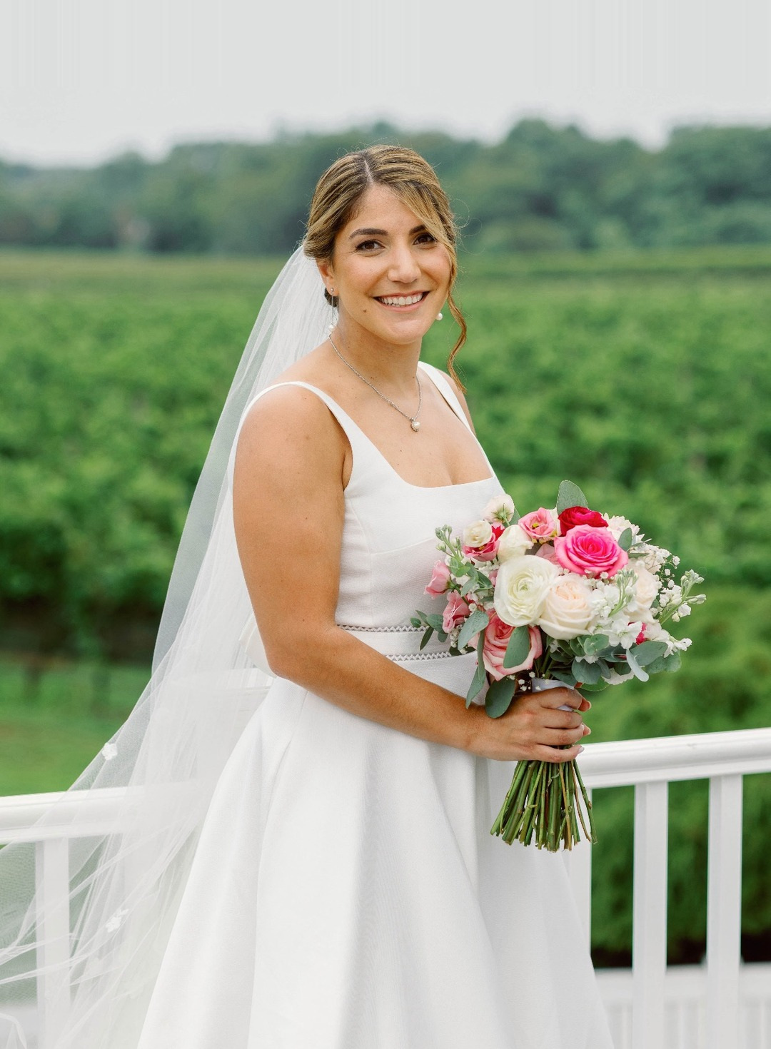 Bride holding a pink and white bouquet at a vineyard