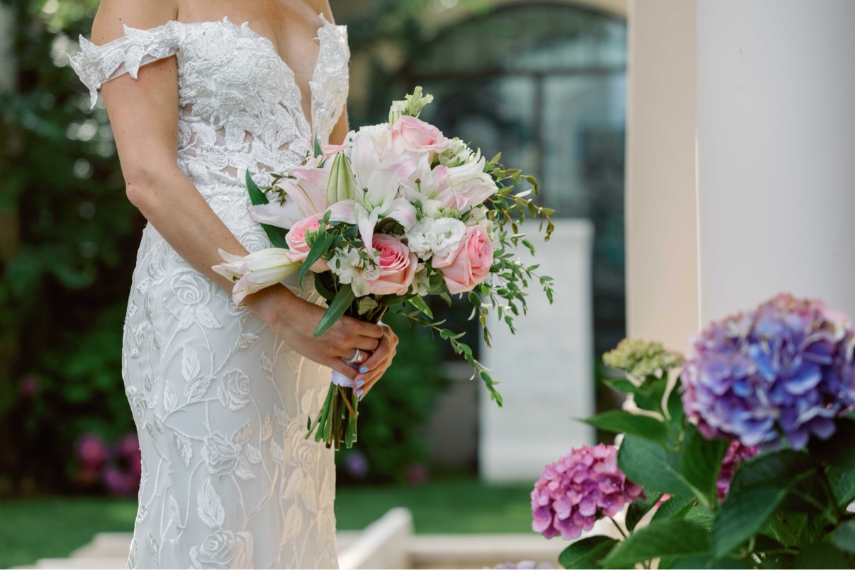 Bride’s lace wedding dress with a pink and white bouquet
