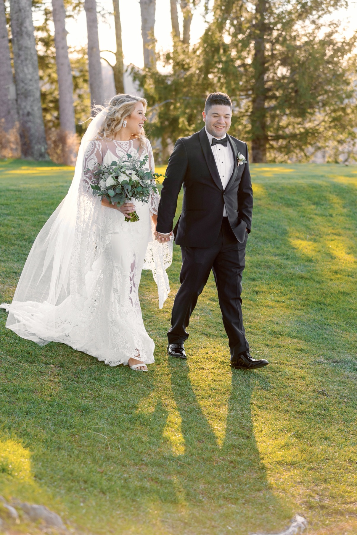 Newlyweds strolling across a sunlit vineyard lawn